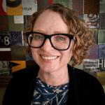 Smiling woman with curly red hair and glasses