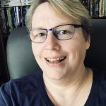 Smiling woman with glasses and short blonde hair